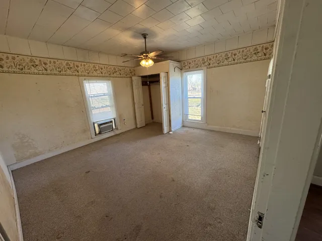 en empty room with windows and ceiling fan