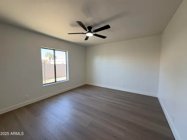 an empty room with wooden floor fan and windows