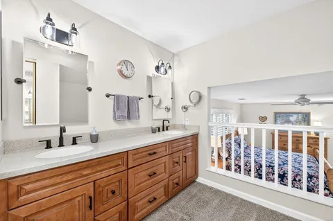a spacious bathroom with double vanity sinks a mirror a lamp and a shower