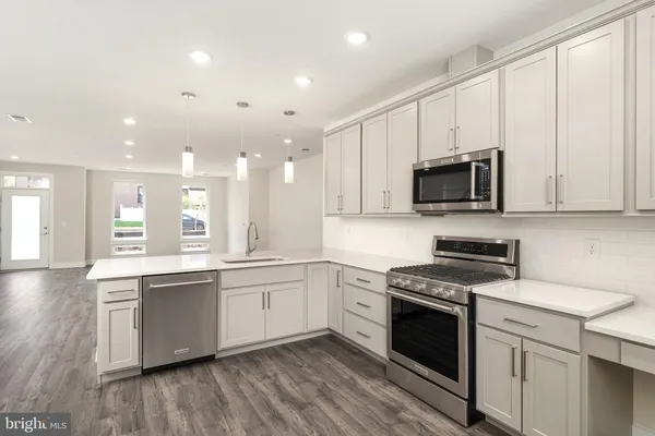a kitchen with stainless steel appliances a white stove top oven a sink and dishwasher with wooden floor