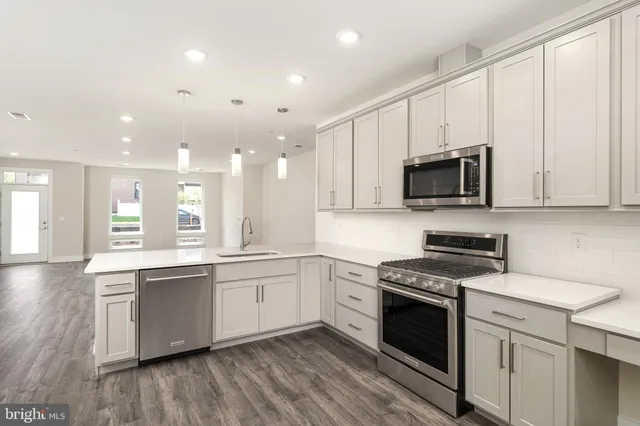 a kitchen with stainless steel appliances a white stove top oven a sink and dishwasher with wooden floor
