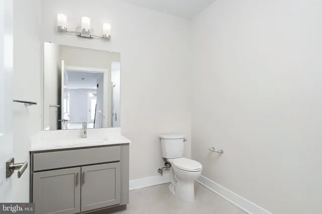 a bathroom with a toilet sink vanity and mirror