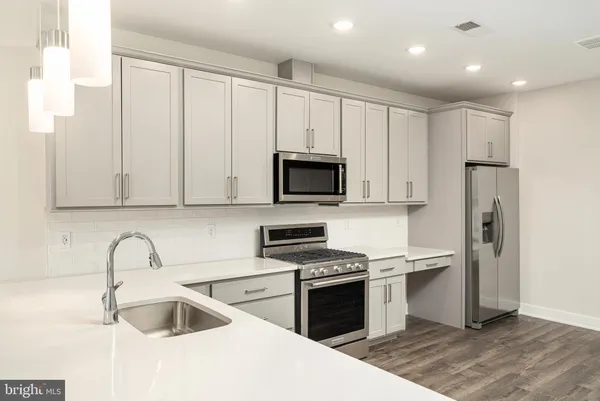 a kitchen with stainless steel appliances granite countertop a sink a stove a refrigerator and a microwave