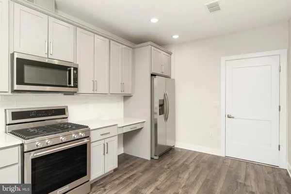 a kitchen with stainless steel appliances white cabinets and a stove top oven