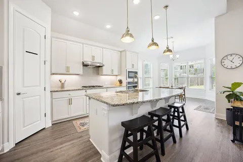 a kitchen with stainless steel appliances granite countertop a kitchen island a stove a table and chairs in it