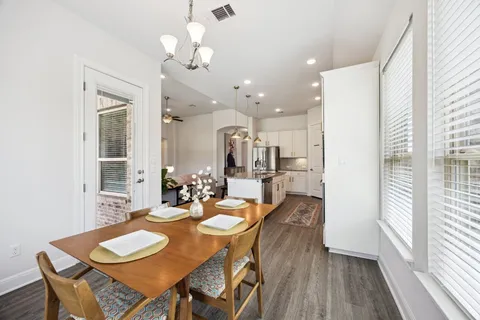 a dining room with wooden floor a chandelier a wooden table and chairs