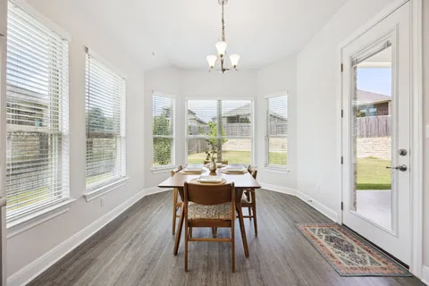 a dining room with wooden floor and a chandelier