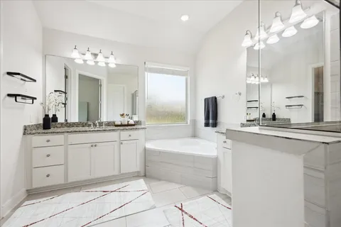 a spacious bathroom with a double vanity sink a mirror a bathtub and a shower