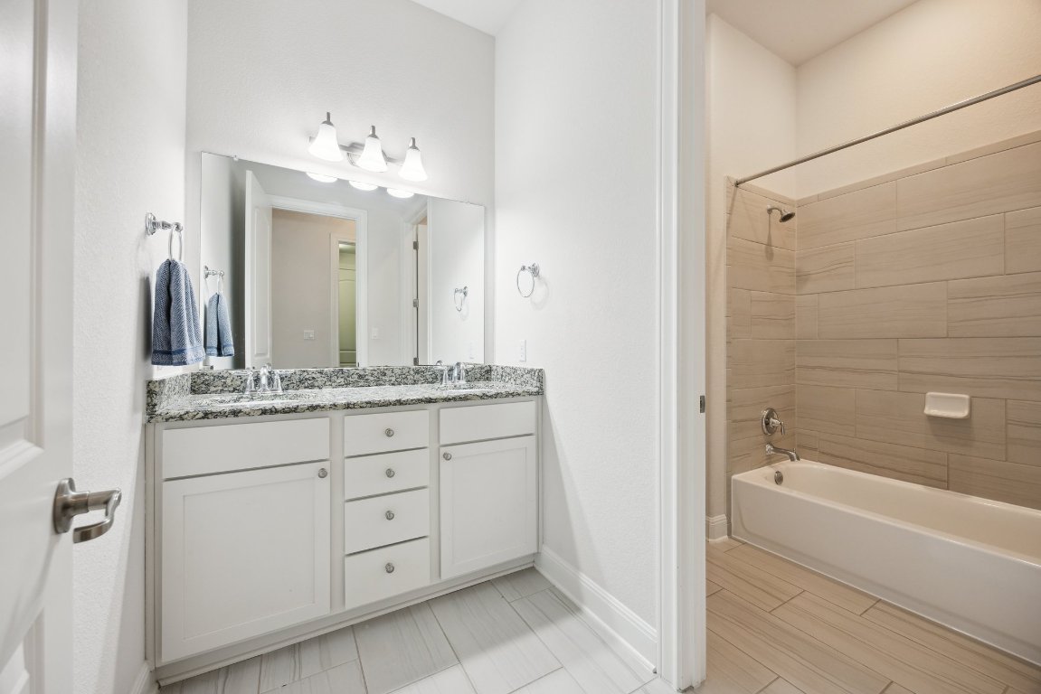 744 Founders Ridge Dripping Springs, TX 78620 - Photo 24 of 32 a bathroom with a granite countertop sink a mirror and a bathtub