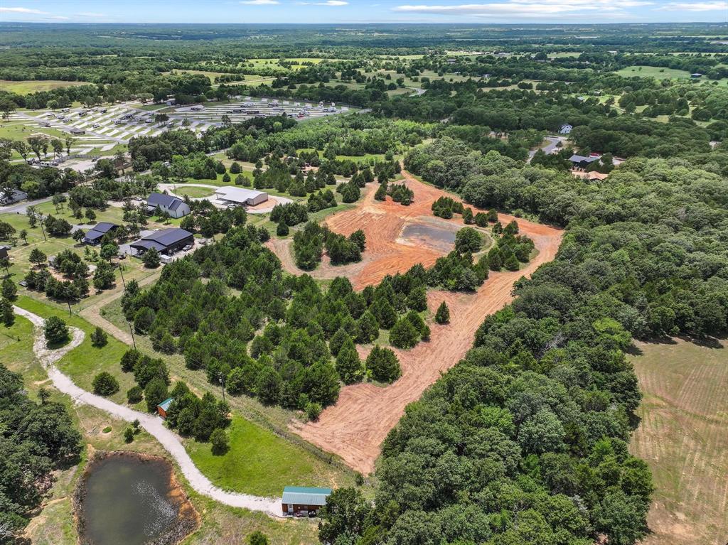 1445 Cedar Mills Road Gordonville, TX 76245 - Photo 9 of 28 Expansive cleared land parcel surrounded by mature trees, featuring a distinct pond