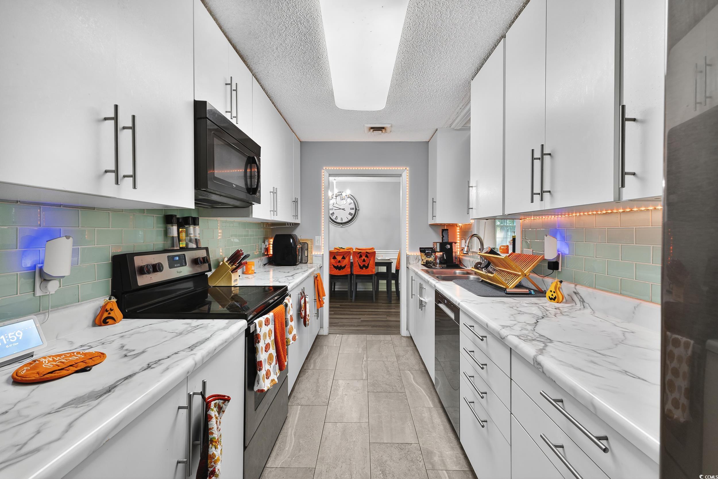 342 Red Fox Road Myrtle Beach, SC 29579 - Photo 12 of 40 Kitchen featuring appliances with stainless steel finishes, white cabinets, and a textured ceiling