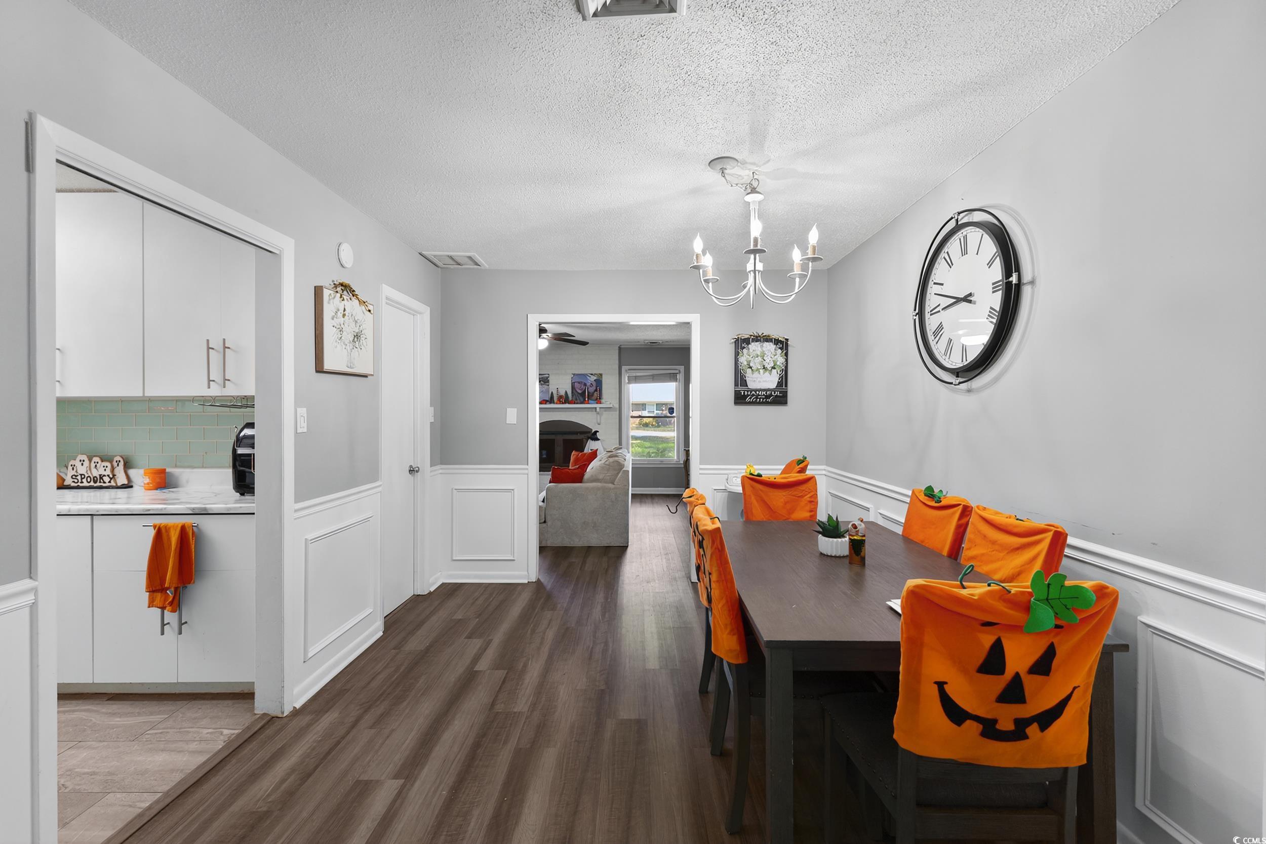 342 Red Fox Road Myrtle Beach, SC 29579 - Photo 15 of 40 Dining area with dark wood-style flooring, a decorative wall, a wainscoted wall, ceiling fan, and a textured ceiling