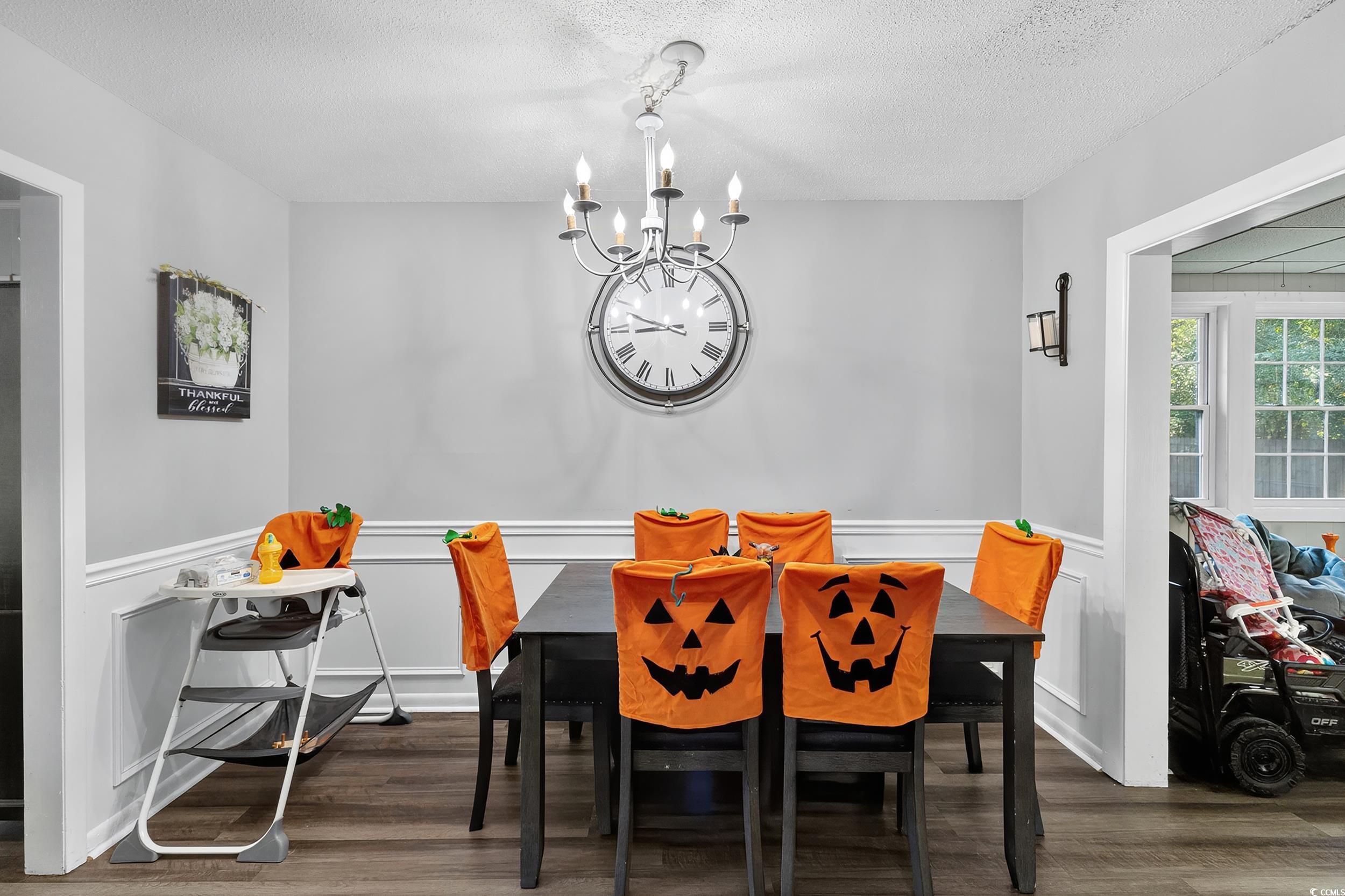 342 Red Fox Road Myrtle Beach, SC 29579 - Photo 17 of 40 Dining space featuring a wainscoted wall, dark wood finished floors, a decorative wall, a chandelier, and a textured ceiling