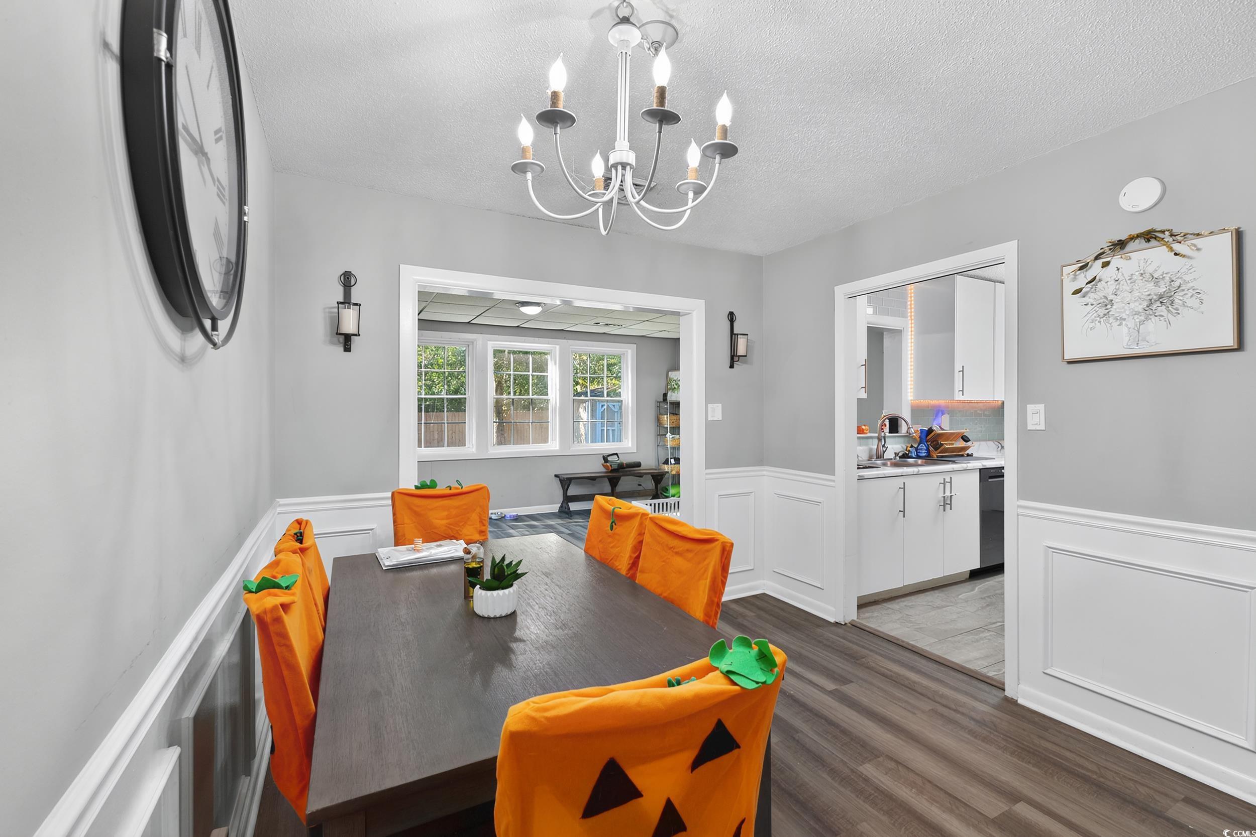 342 Red Fox Road Myrtle Beach, SC 29579 - Photo 18 of 40 Dining space with dark wood-type flooring, a textured ceiling, a chandelier, wainscoting, and a decorative wall