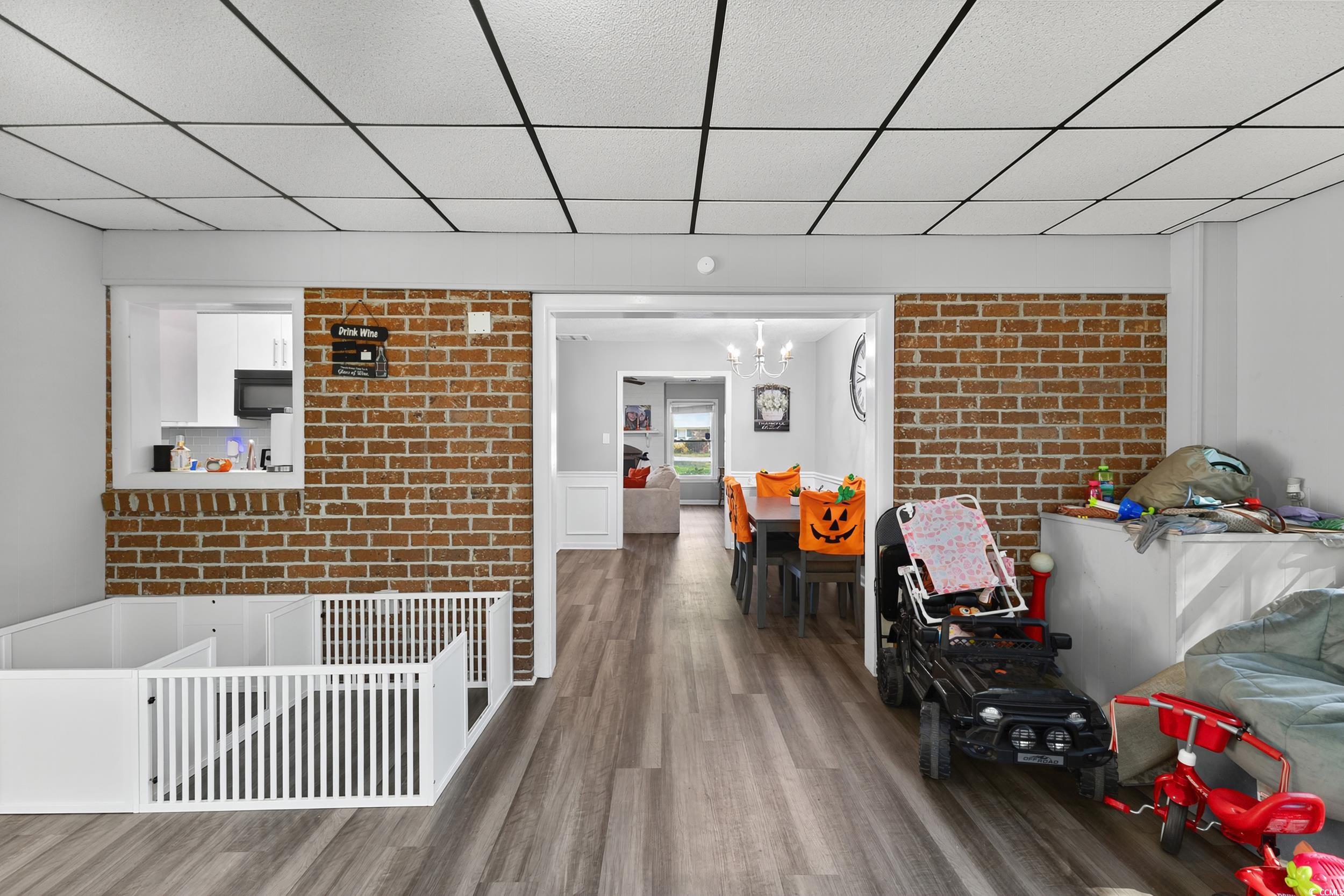 342 Red Fox Road Myrtle Beach, SC 29579 - Photo 23 of 40 Interior space with a paneled ceiling, brick wall, wood finished floors, and a chandelier