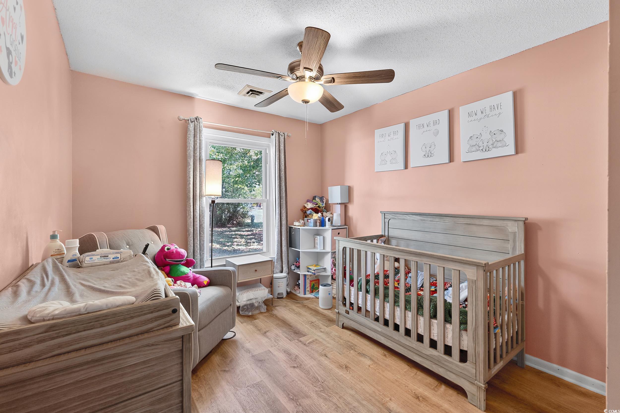 342 Red Fox Road Myrtle Beach, SC 29579 - Photo 28 of 40 Bedroom featuring a nursery area, light wood-type flooring, a textured ceiling, and a ceiling fan