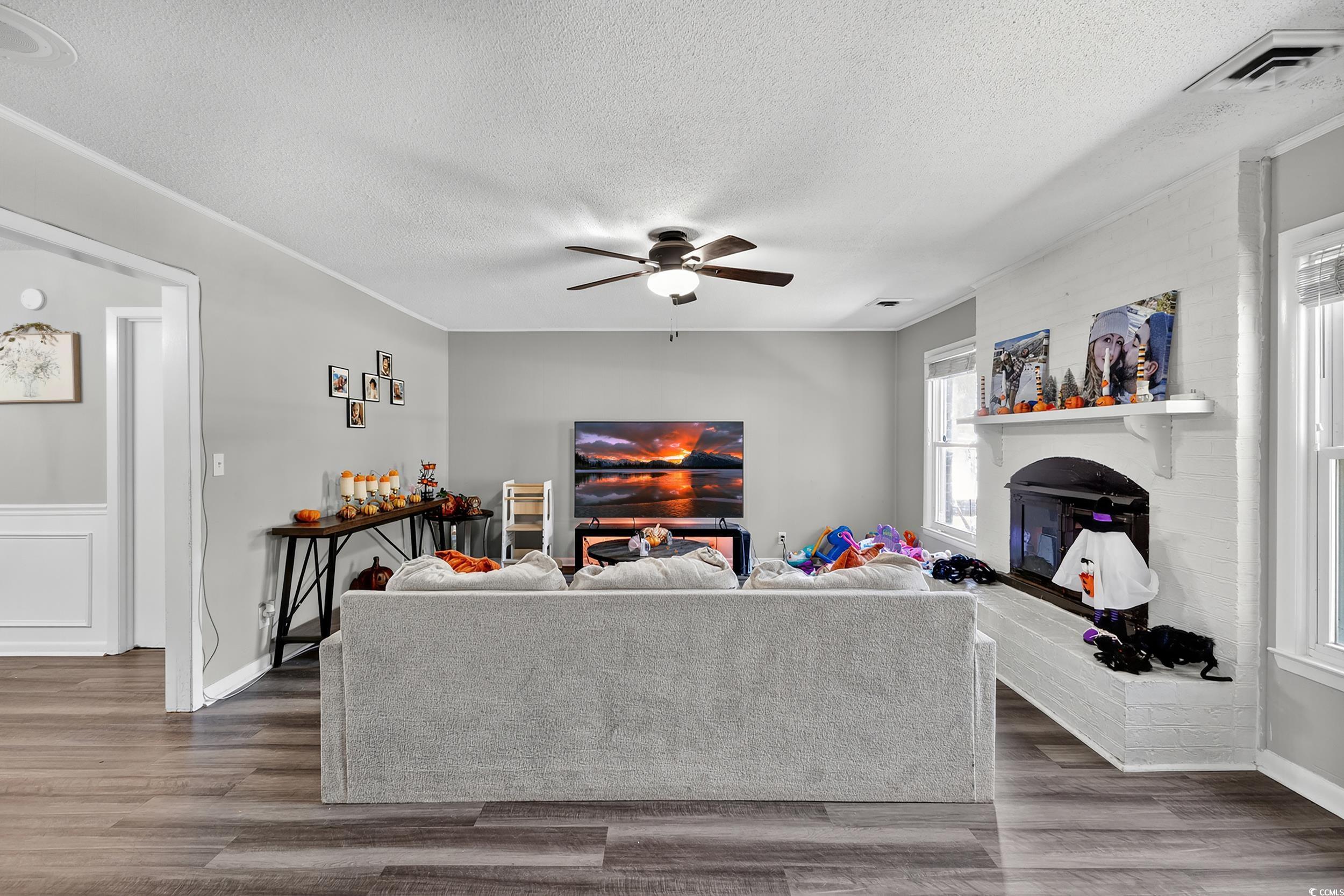 342 Red Fox Road Myrtle Beach, SC 29579 - Photo 3 of 40 Living area featuring a brick fireplace, a textured ceiling, wood finished floors, and ceiling fan