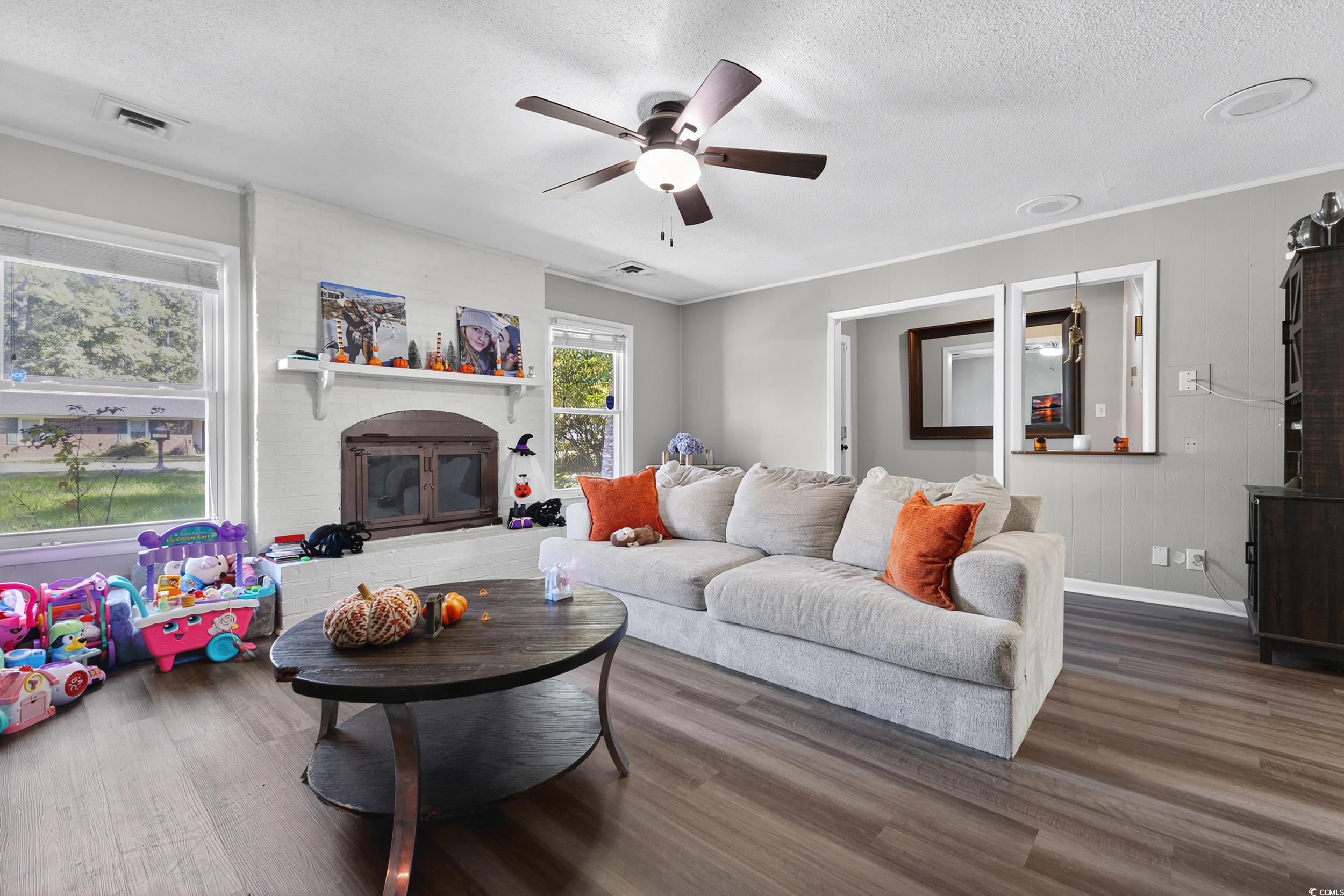 342 Red Fox Road Myrtle Beach, SC 29579 - Photo 7 of 40 Living room featuring wood finished floors, a textured ceiling, ceiling fan, a brick fireplace, and ornamental molding