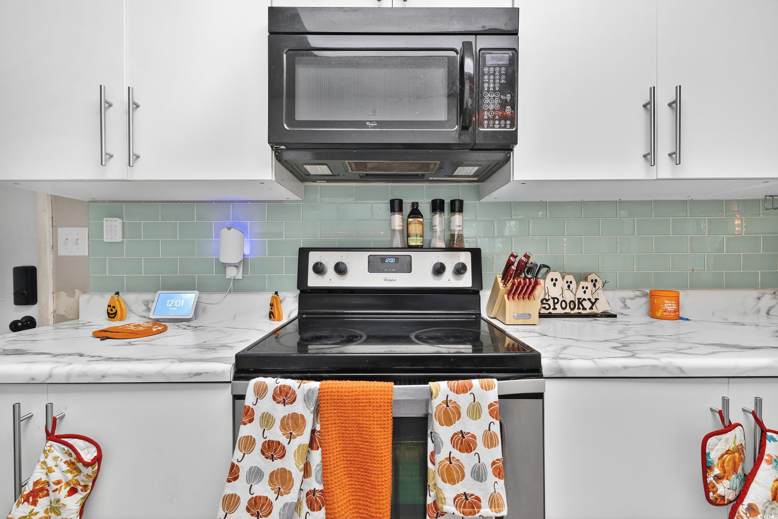 342 Red Fox Road Myrtle Beach, SC 29579 - Photo 10 of 40 Kitchen with range with electric cooktop, white cabinetry, black microwave, backsplash, and light stone countertops