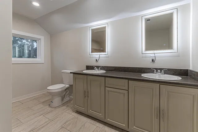 a bathroom with a granite countertop toilet a sink and a mirror