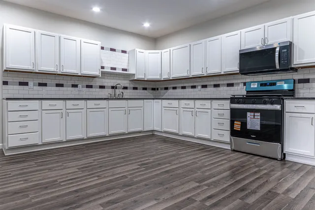 a kitchen with stainless steel appliances granite countertop a stove a sink and white cabinets