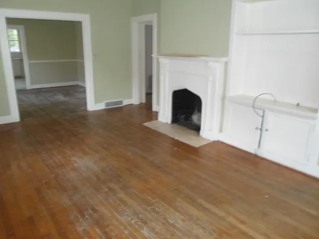 a view of empty room with wooden floor and fireplace