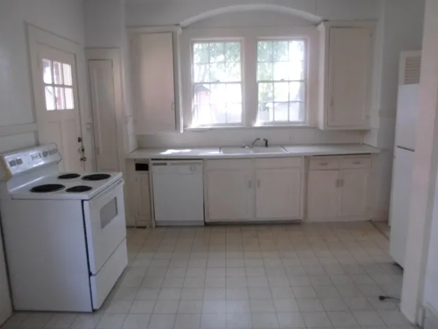 a kitchen with granite countertop white cabinets and white appliances