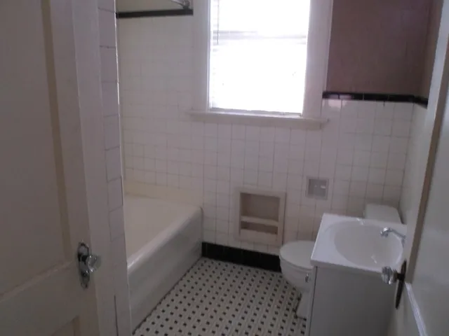 a bathroom with a sink a toilet a window and bathtub