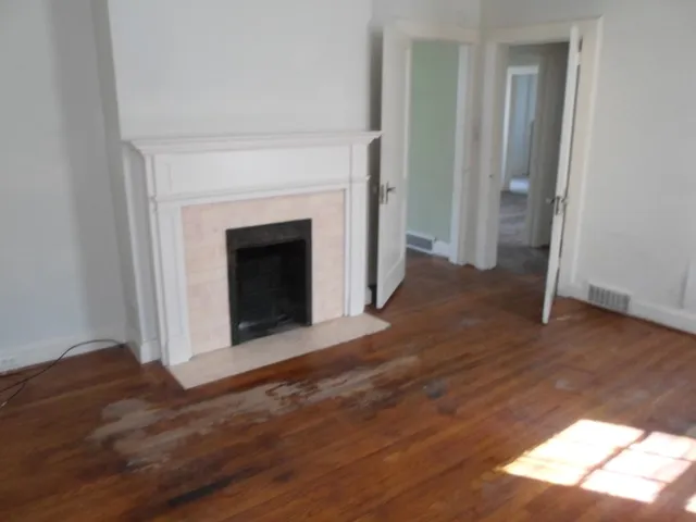 a view of a livingroom with wooden floor and a fireplace