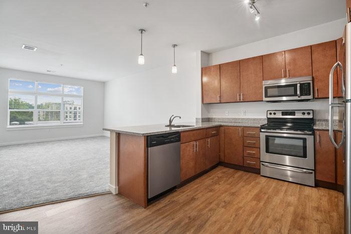 131 Bridge Street, Unit 2B11219 Phoenixville, PA 19460 - Photo 13 of 104 a kitchen with stainless steel appliances kitchen island granite countertop a stove a sink and a microwave
