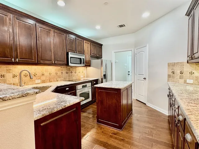 a kitchen with granite countertop wooden cabinets a sink and appliances