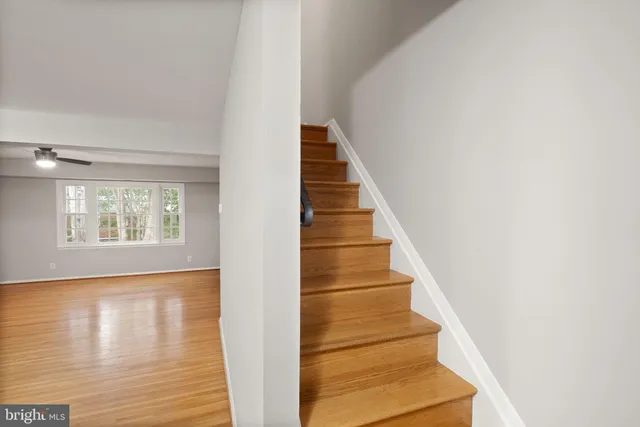 a view of a hallway with wooden floor and a bathroom