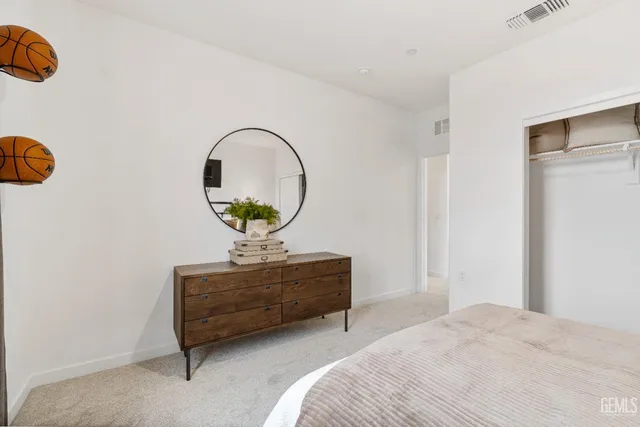 a bedroom with a bed a dresser and a potted plant