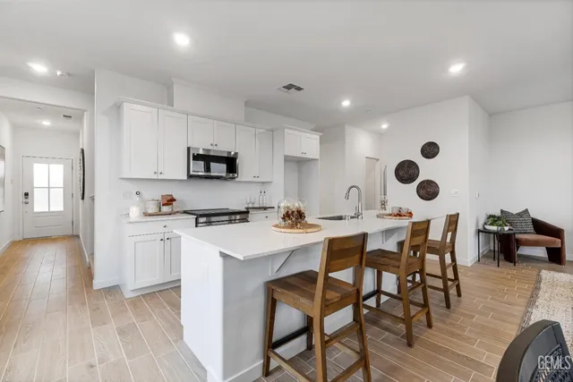 a kitchen with stainless steel appliances granite countertop a stove a sink a microwave a dining table and chairs with wooden floor