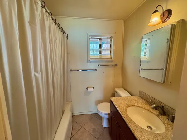 a bathroom with a granite countertop toilet sink and mirror