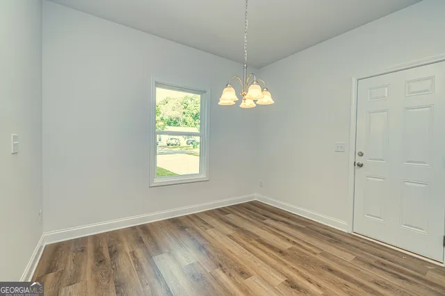 an empty room with wooden floor exposed radiator and windows