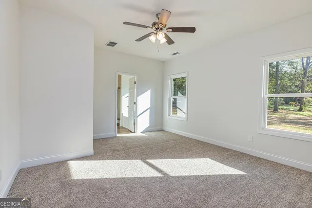 an empty room with windows and ceiling fan
