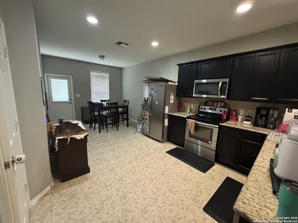 a kitchen with stainless steel appliances kitchen island granite countertop a refrigerator and a stove top oven