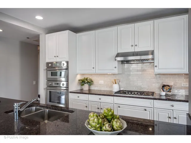 a kitchen with stainless steel appliances kitchen island granite countertop a refrigerator and a stove top oven