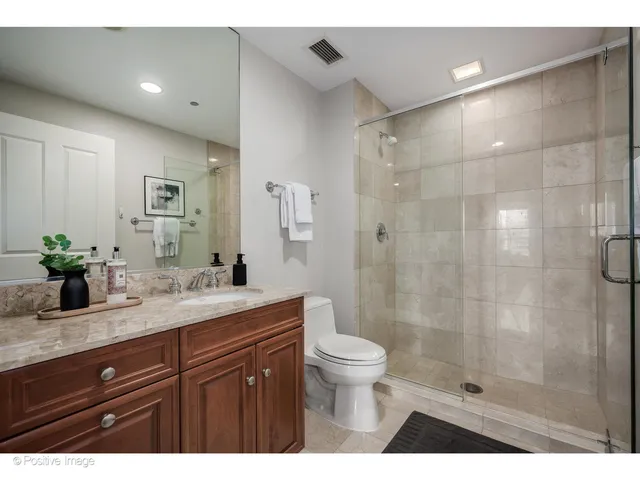 a bathroom with a granite countertop sink a toilet and shower