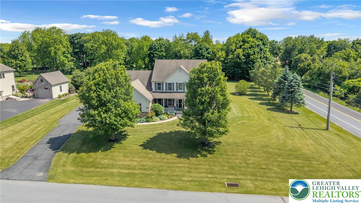 204 Bushkill Ridge Road Wind Gap, PA 18091 - Photo 3 of 48 A classic two-story residence with a welcoming front porch, surrounded by mature trees and lush green lawns.