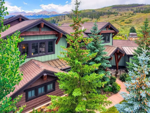 a view of wooden house with a small yard plants and large tree