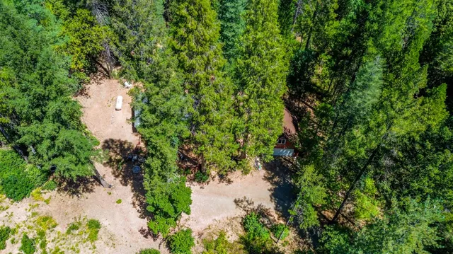 an aerial view of residential house with outdoor space and trees all around