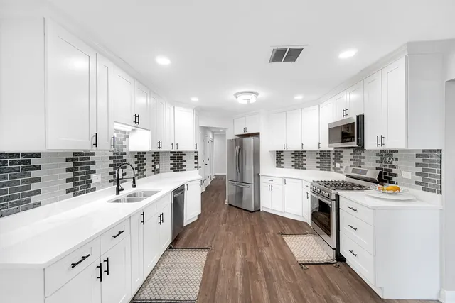 a kitchen with stainless steel appliances a sink cabinets and wooden floor
