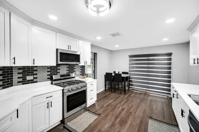 a kitchen with granite countertop a stove top oven a sink dishwasher and a refrigerator with wooden floor