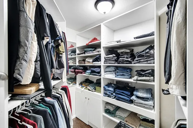 a view of walk in closet with clothes and shoes