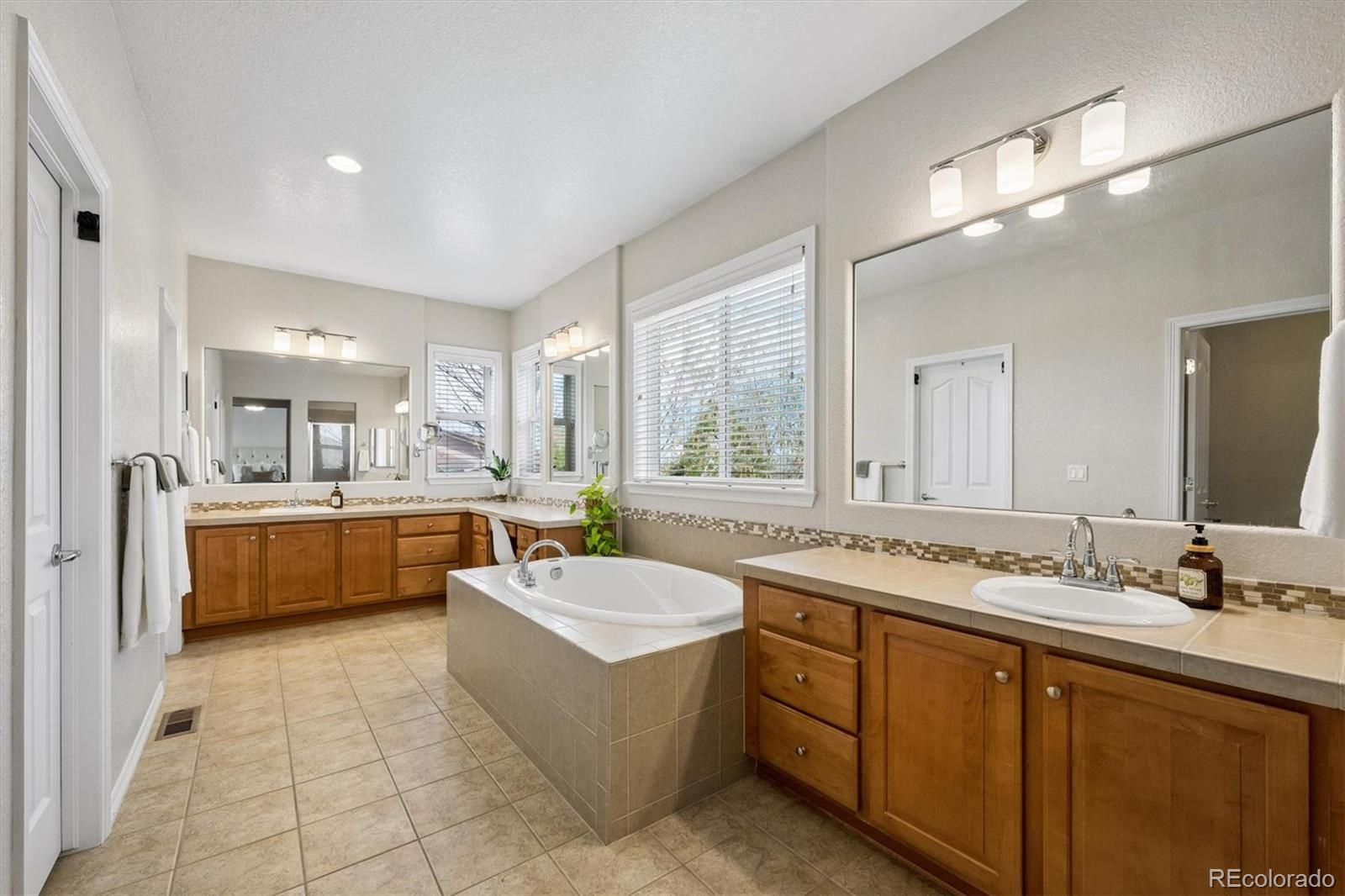 2677 Pemberly Avenue Highlands Ranch, CO 80126 - Photo 27 of 50 a large spacious bathroom with a double vanity sink a mirror a bathtub and window