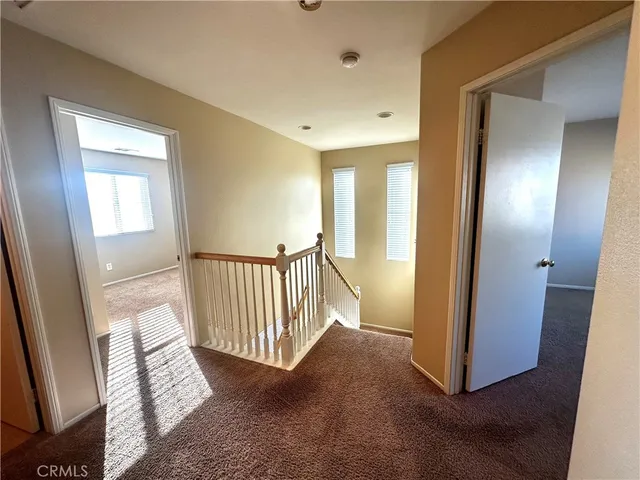 a view of a hallway with wooden floor and stairs