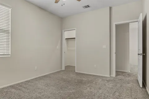 an empty room with a chandelier fan and windows