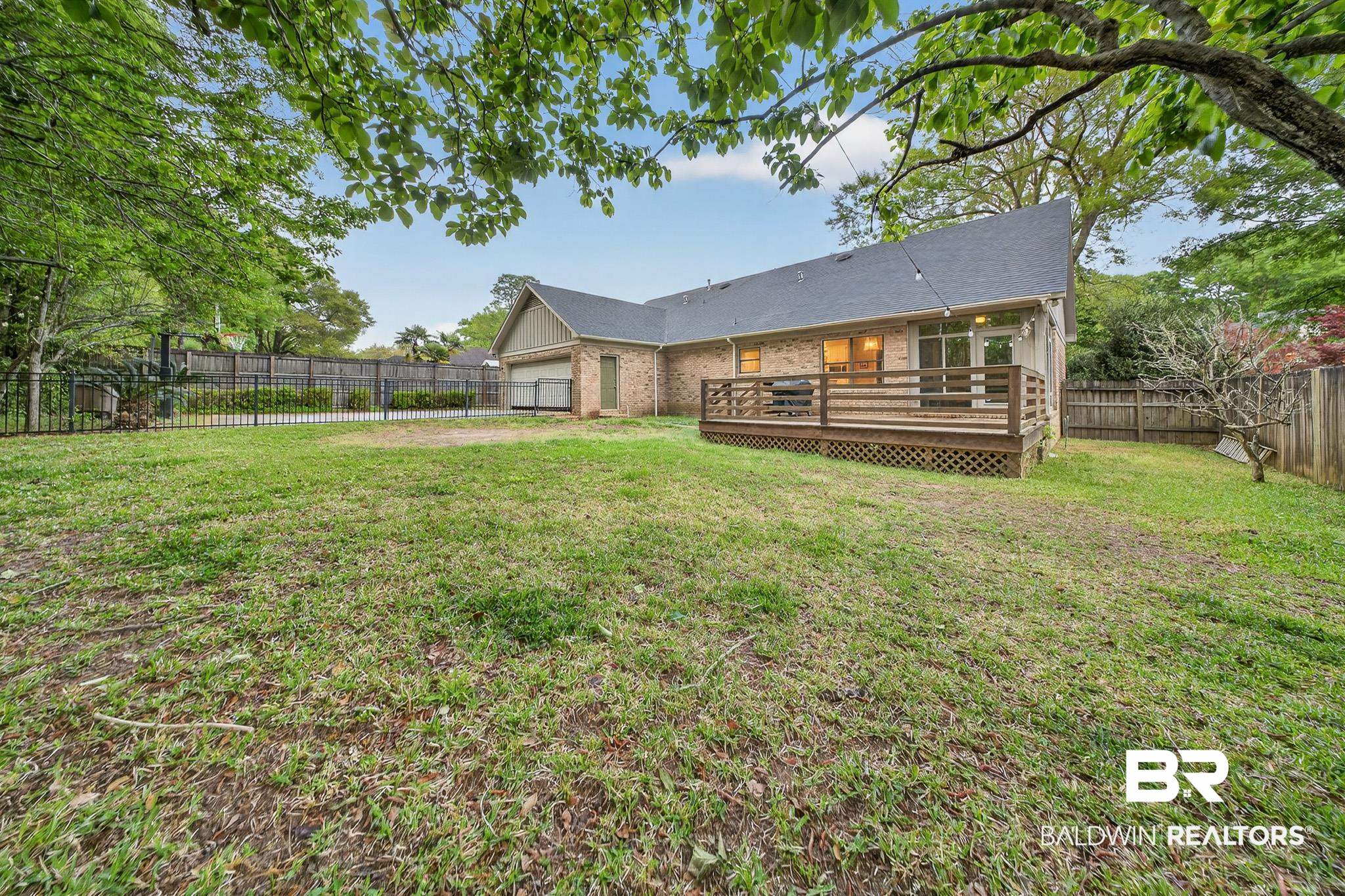 1250 Savannah Drive Mobile, AL 36609 - Photo 32 of 35 Back of property featuring a deck, a fenced backyard, brick siding, a garage, and roof with shingles